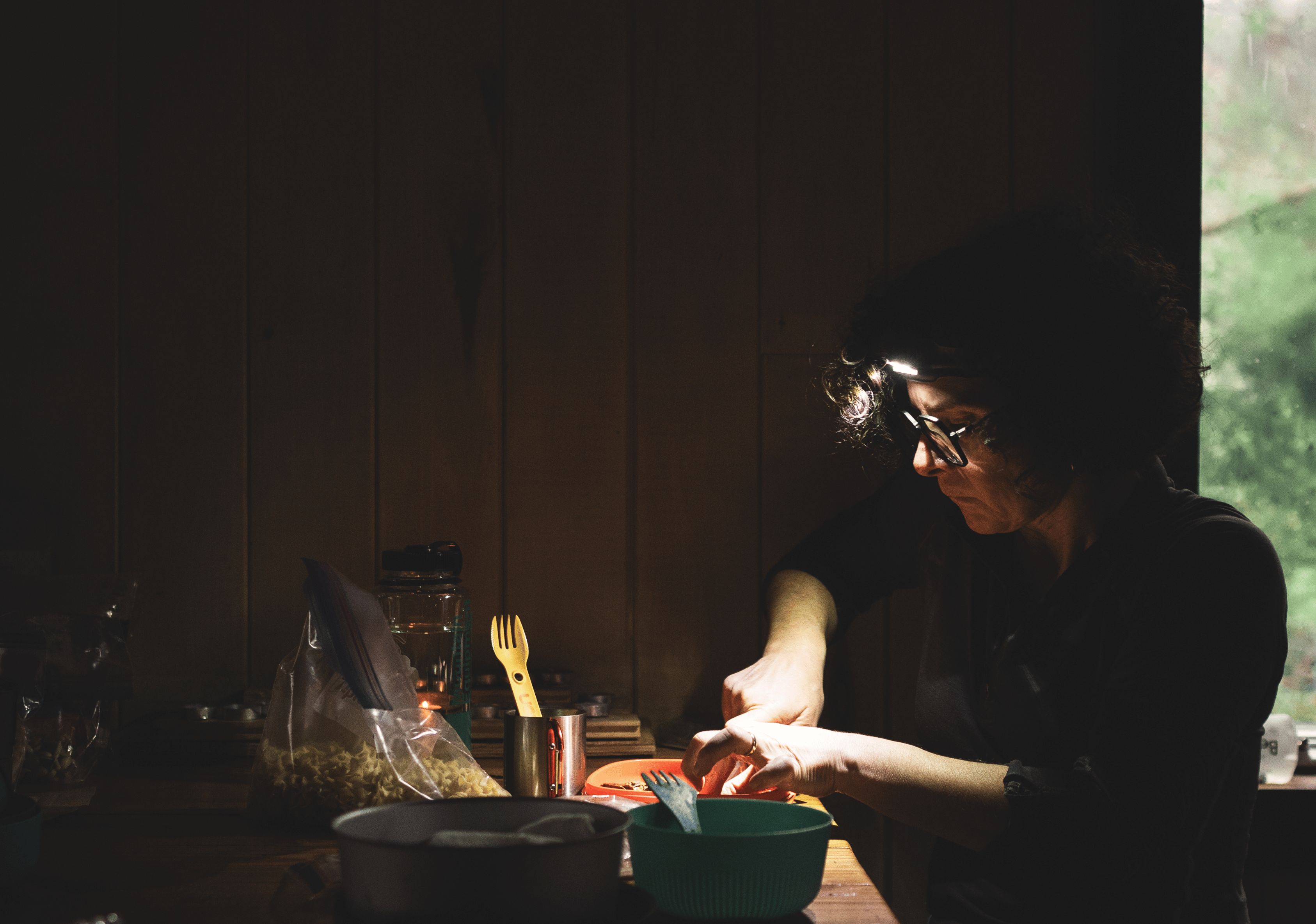 Femme portant une lampe éclairant la table d'un refuge rustique pour cuisiner