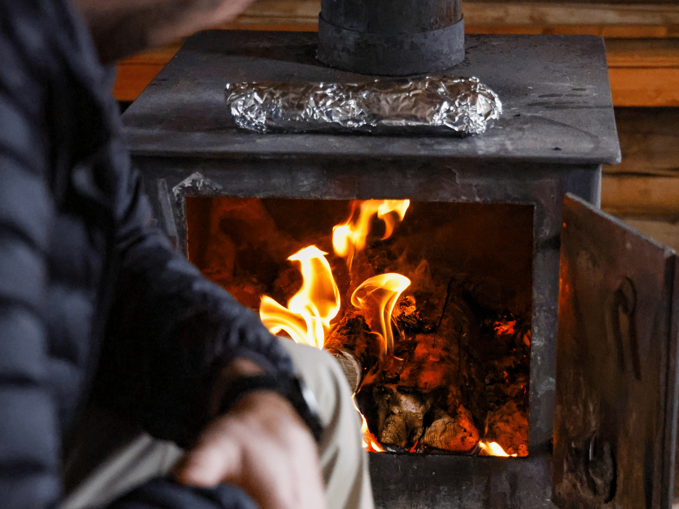 Poêle à bois allumé dans un chalet rustique, ambiance chaleureuse après une journée plein air à la Vallée Bras-du-Nord