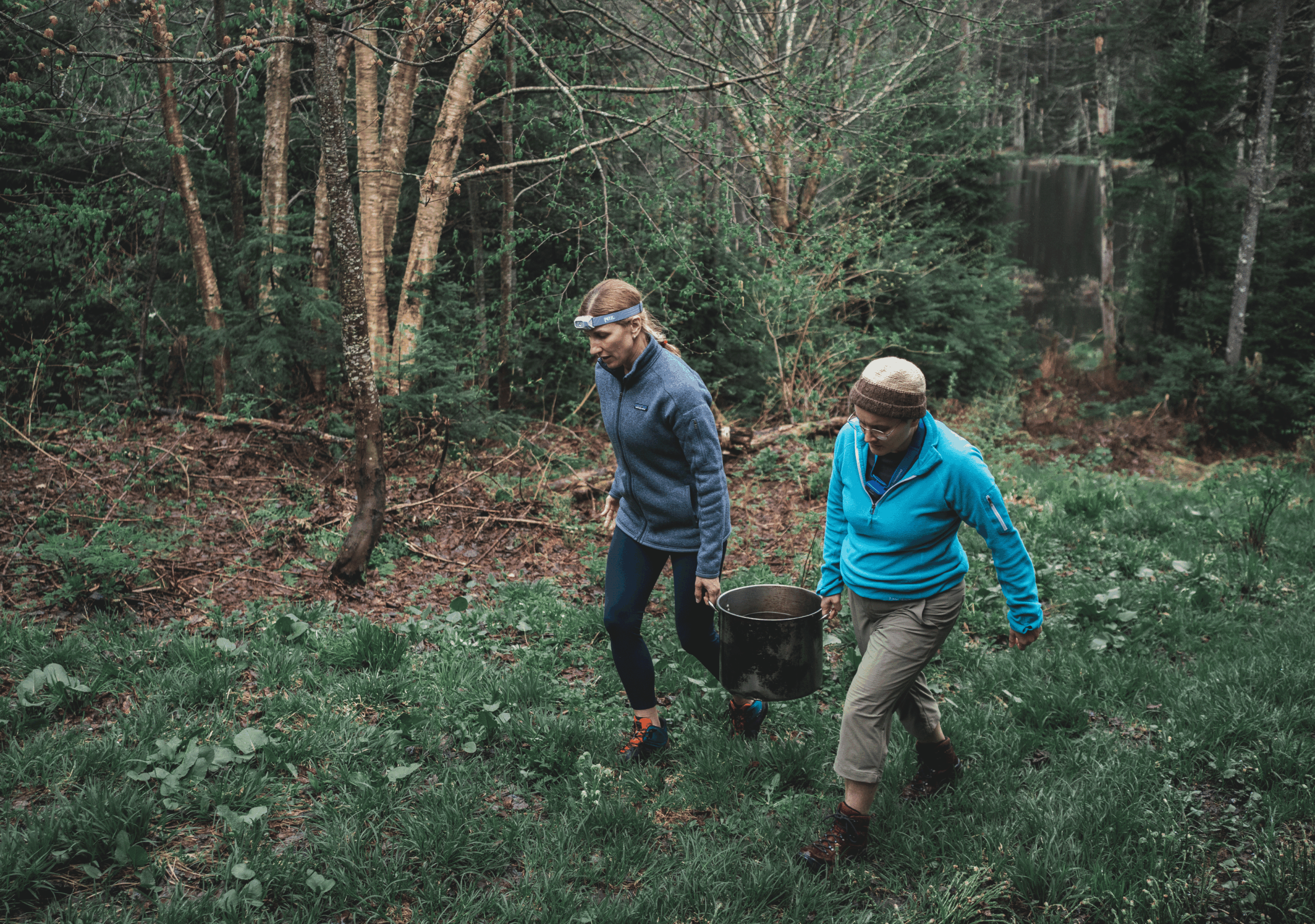 Deux randonneuse transportant un seau d'eau en forêt