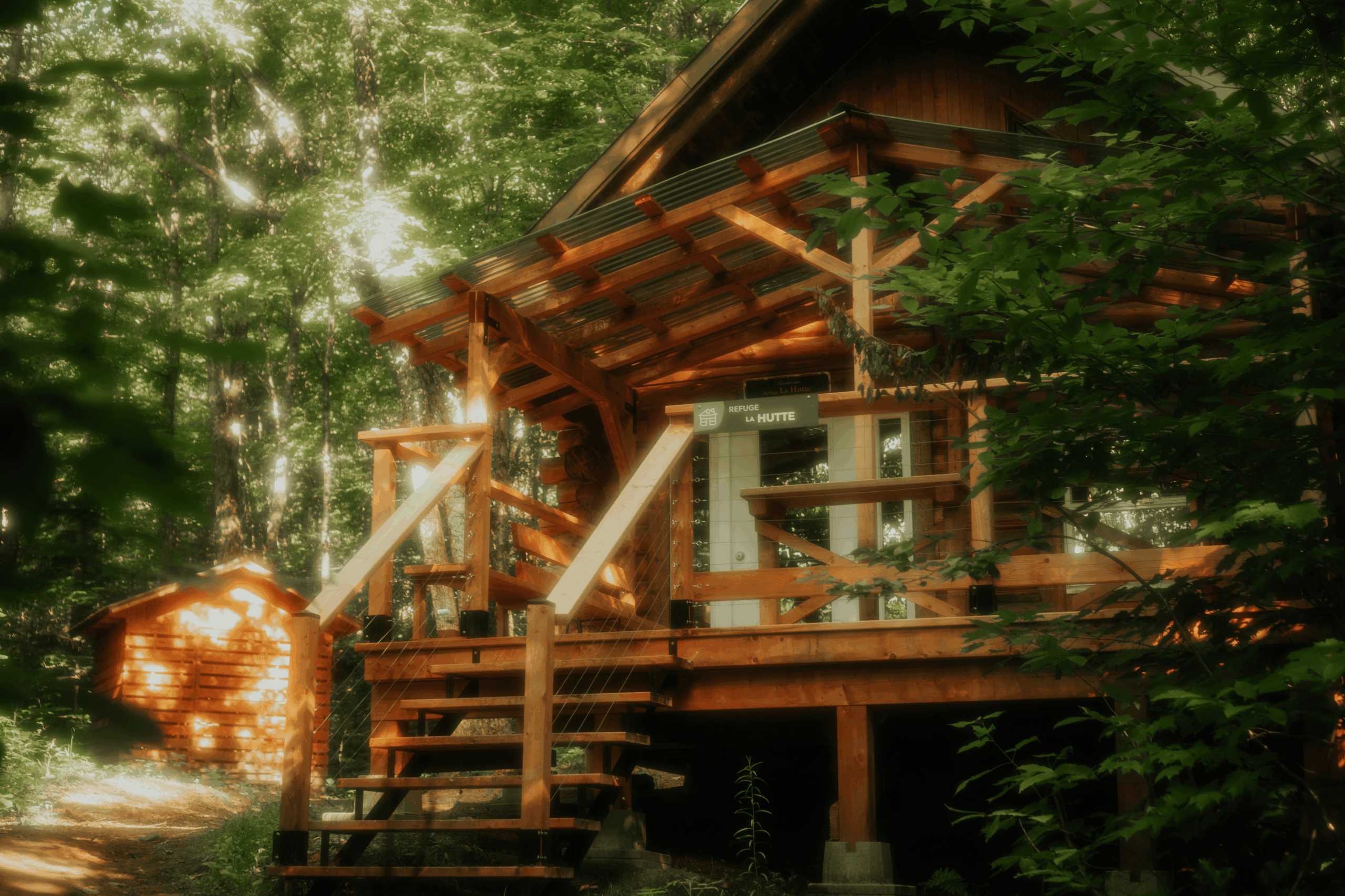 Refuge La Hutte avec terrasse couverte en bois, niché au cœur de la forêt à la Vallée Bras-du-Nord.