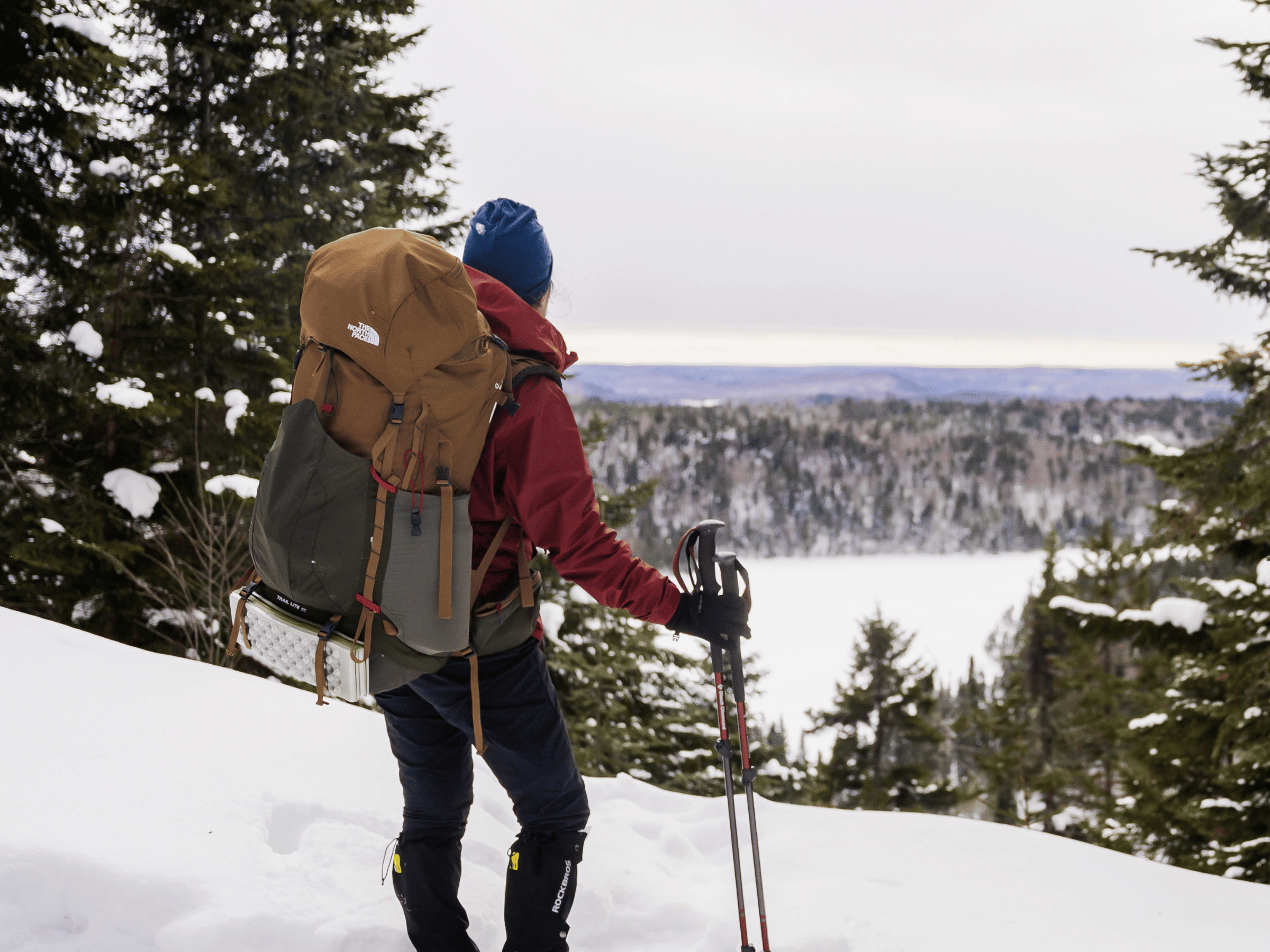 Randonneuse en raquettes admirant la vue panoramique sur la forêt enneigée à la Vallée Bras-du-Nord au Québec.
