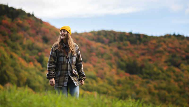 Young woman on the Montagne Art trail, in the middle of autumn, taking advantage of a beautiful day to enjoy an outdoor activity on one of the Valley's hiking trails.