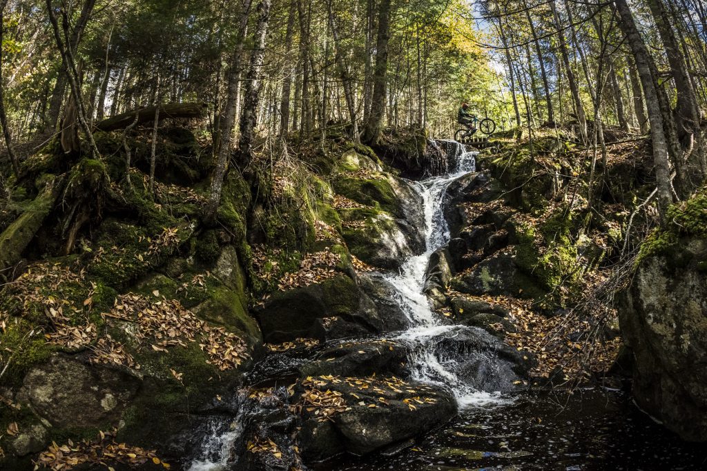 View of a cyclist enjoying an outdoor activity, at the top of a waterfall surrounded by nature, in the Neilson sector, ideal for adventure lovers and more experienced cyclists.