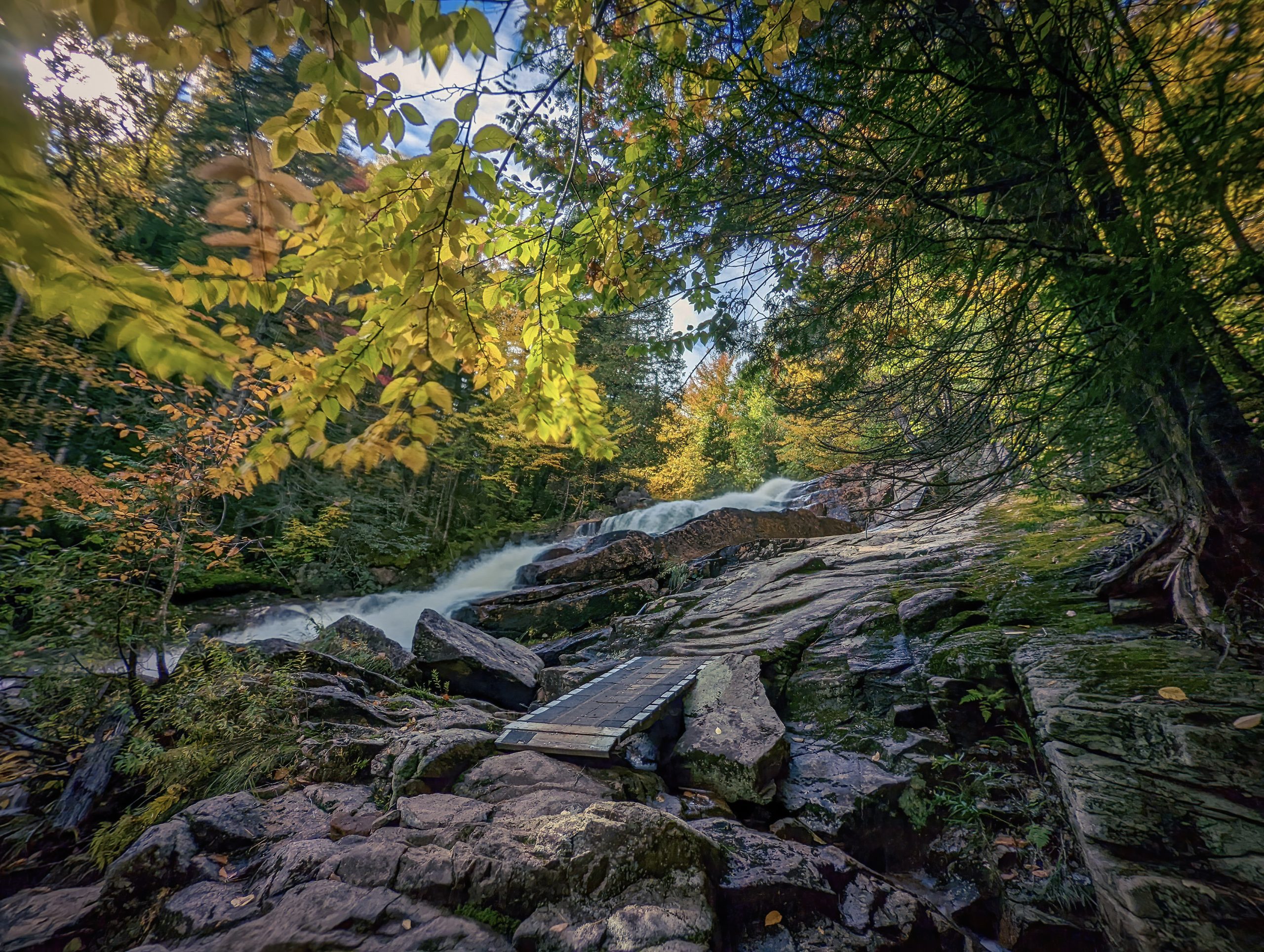Landscape of the Légende trail, one of the most epic trails in Quebec, with its rocky course, waterfall and lush greenery.