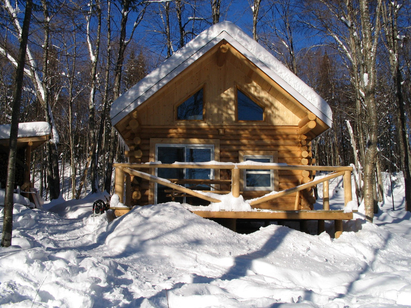 Façade du refuge La Hutte en hiver, en pleine nature hivernale. La Hutte est l'un des hébergements de type refuge offert par la Vallée pour vous adonner à vos activités de plein air.