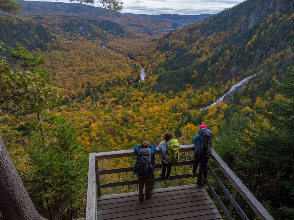 Famille admirant le paysage époustouflant s'offrant à eux à partir d'un observatoire situé sur l'un des sentiers de randonnées pédestres disponibles à la Vallée et profitant de la vue des montagnes, de la nature et de la forêt pour faire le plein de plein air.