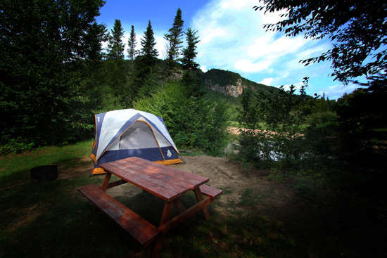 Vue d'une tente au Camping Etsanha derrière une table à pique-nique, hébergement partenaire de la Vallée, l'un des types d'hébergements idéaux pour pratiquer vos activités de plein air entouré par la nature.