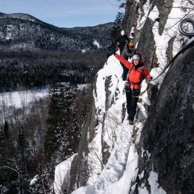 A couple of adventurers wave as they practice the winter Via Ferrata, an activity offered by the Valley for fans of extraordinary sports.