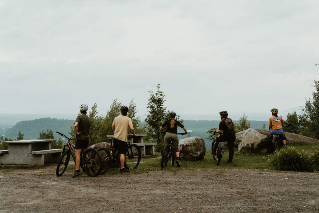 Groupe de cycliste de montagne chevauchant leur vélo au sommet d'une montagne et regardant le paysage à l'horizon
